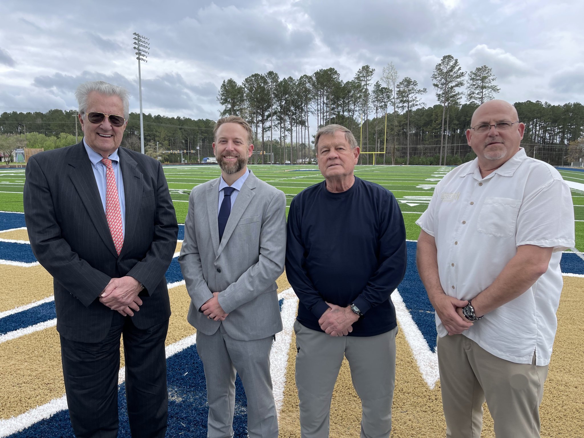 (L to R) Don Stallings, Dr. Evan D. Duff, Marion Barnes and Jeff Filkovski stand on the new Stallings Turf Field at Vernon T. Bradley, Jr. Stadium